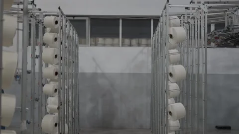 Textile factory aisle with yarn spools on metal racks Stock Footage 327449255