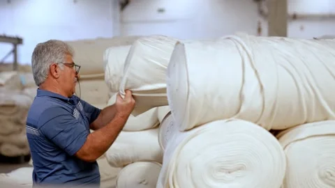 Textile Factory Worker Inspecting Fabric Rolls Human Labor in Production Stock Footage 329678883