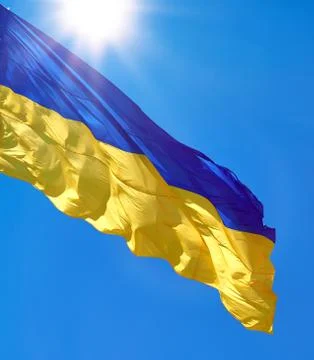 Textile flag of Ukraine develops against a clear blue sky Stock Photos
