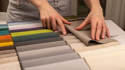 Textile material sample catalog for sofa upholstery choice. Tailor hands in.. Stock Photos