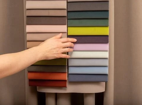 Textile material swatch catalog hanging in showroom studio. Hand touching s.. Stock Photos