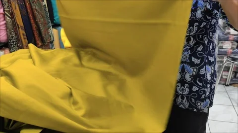 Textile Store Workers Unrolling Vibrant Yellow Fabric for Selection Stock Footage 294977511