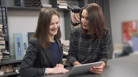 A textile studio consultant shows a visitor product samples on a tablet. Stock Footage 105080806