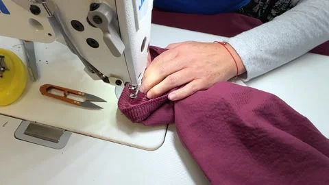 Textile worker using a sewing machine to create professional garments. Precision Stock Footage 312565725