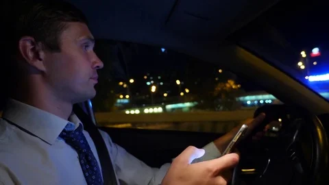 Texting with a smart phone in car. a young businessman is driving a car around Stock Footage 80924012