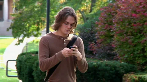 Texting Student Mesmerized by his Cellphone while Walking on Campus Stock Footage 531165