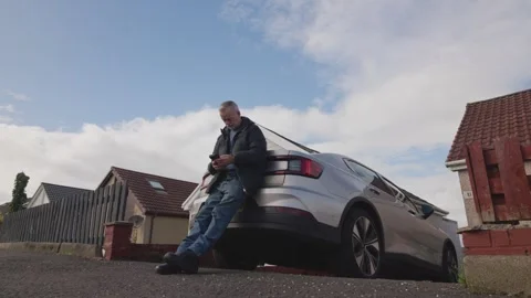 Texting Using Smartphone While Leaning Against Modern Electric Car Vidéo 347017026
