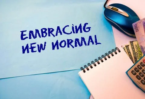 Texts embracing new normal on blue paper. Note pad, calculator and mouse. Stock Photos