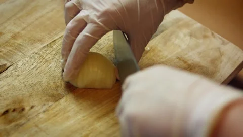 Textural gloved hands slicing a peeled onion with a chef knife in low angle, 4K Stock Footage 341110065