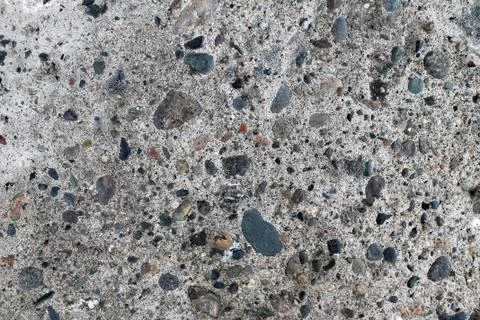 Textural grey cement background with nature pebbles Stock Photos