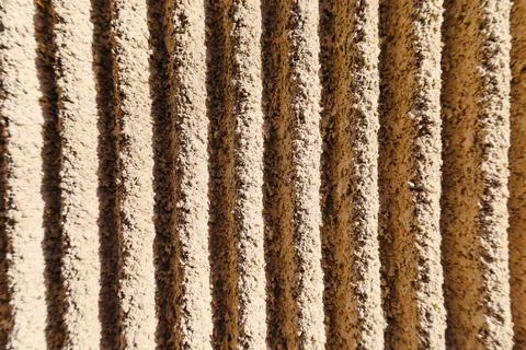 Textural patterns emerge on a sunlit wall displaying elegant lines and shad.. Stock Photos