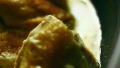 Textural spoon coating roasted poultry with pale gravy in top view, 4K Stock Footage 341105960