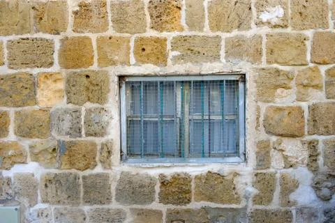 Texture of the ancient stone wall of the ancient city and a window with a lat Stock Photos