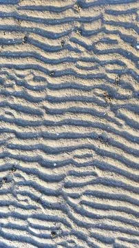 The texture of the beach soil forms a natural pattern due to sea water and .. Stock Photos