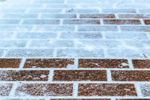 The texture of the cobblestone path covered with the first snow in winter. Stock Photos