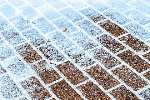 The texture of the cobblestone path covered with the first snow in winter. Stock Photos