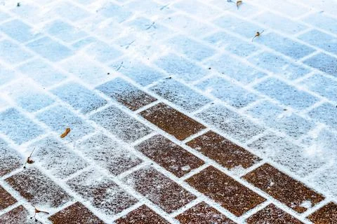 The texture of the cobblestone path covered with the first snow in winter. 스톡 사진