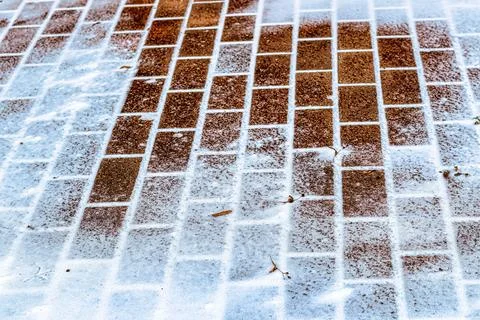 The texture of the cobblestone path covered with the first snow in winter. Stock Photos