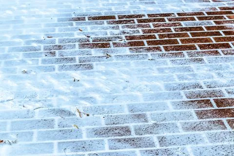 The texture of the cobblestone path covered with the first snow in winter. Stock Photos