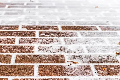 The texture of the cobblestone path covered with the first snow in winter. Stock Photos