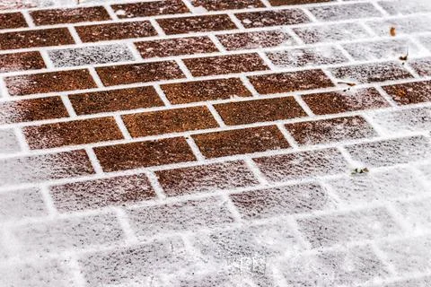 The texture of the cobblestone path covered with the first snow in winter. Stock Photos