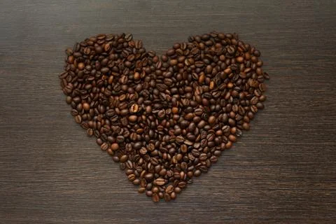 Texture of coffee beans in heart shape on dark wooden surface Stock Photos