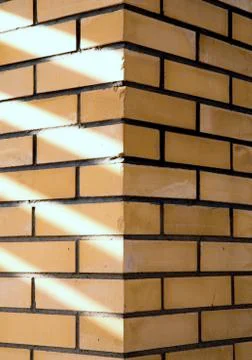 Texture of a corner of a brick wall with rays of sunlight Stock Photos