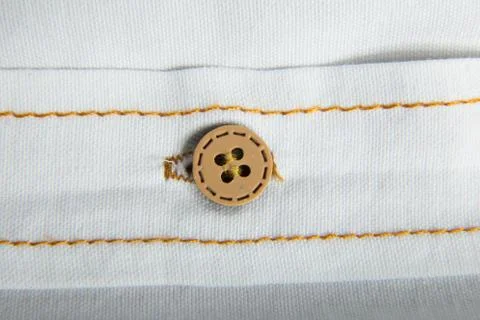 Texture of a cotton fabric as a background. Brown button. Extremely close-up. Stock Photos