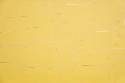 The texture of a cracked yellow surface as a close-up background with space to Stock Photos
