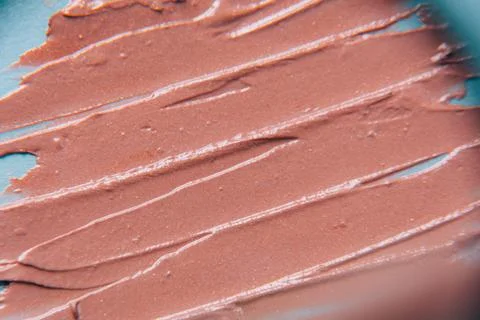 The texture of the foundation is beige under the make-up on a blue background. Stock Photos
