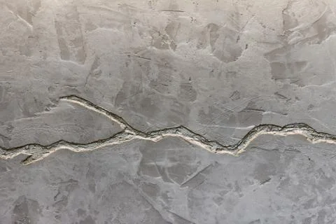 The texture of the gray concrete wall is decorated with a deep crack of silve Stock Photos