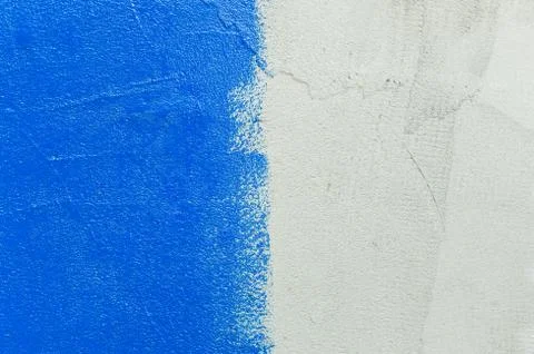 Texture of a gray rough wall that is half painted with bright blue paint Stock Photos