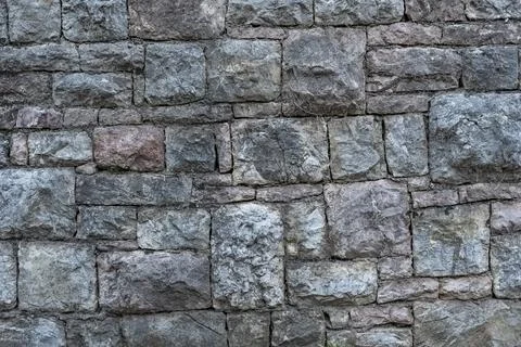 Texture of a grey stone wall made of stones with concrete. Stock Photos