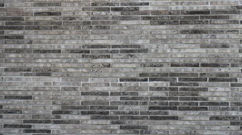 Texture of a heather-toned wall made of narrow gray bricks Stock Photos