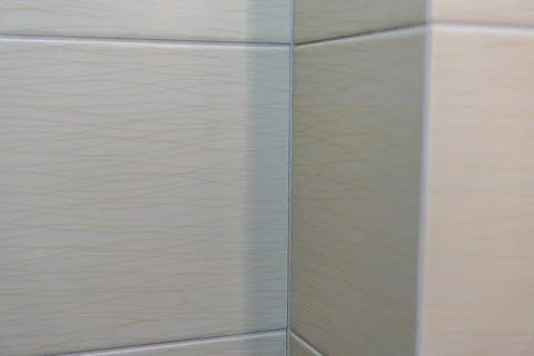 Texture of light-colored tiles with subtle wavy patterns visible in a corner 库存照片