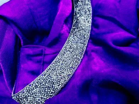 The texture of a lilac folded fabric with a shiny border of beads with rhines Stock Photos