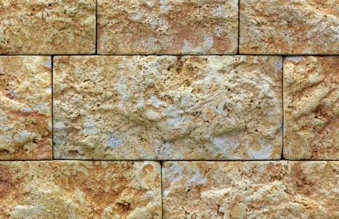 The texture of the limestone stone wall, building stone of beige-golden limes 스톡 사진