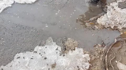 The texture of a muddy puddle with snow, ice and debris, spring snowmelt, out Stock Photos