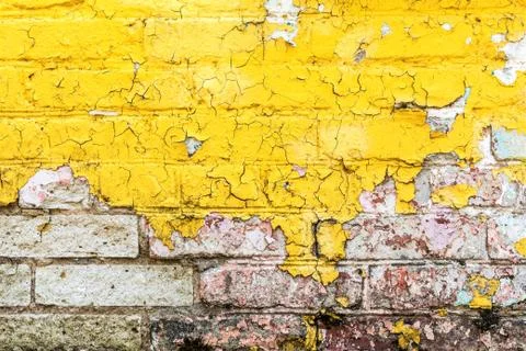 Texture old brick wall painted yellow paint, peeling and crumbling paint on w Stock Photos