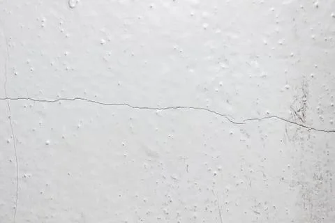 The texture of an old painted white wall with a crack in the middle. Foto stock