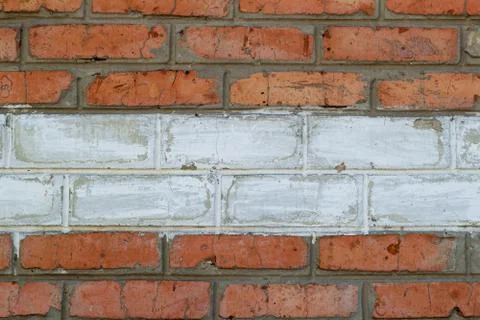 Texture of an old red brick wall background with a strip of white paint Foto stock