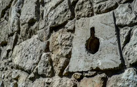 The texture of an old stone wall with a hole for defensive guns Stock Photos