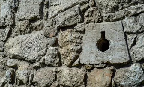 The texture of an old stone wall with a hole for defensive guns Stock Photos
