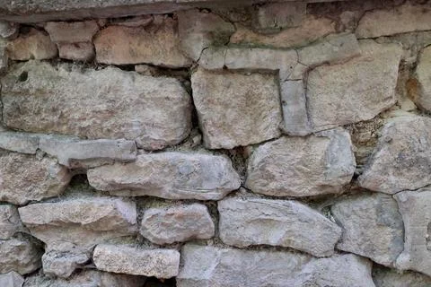 Texture of an old stone wall made of rough, uneven blocks Stock Photos