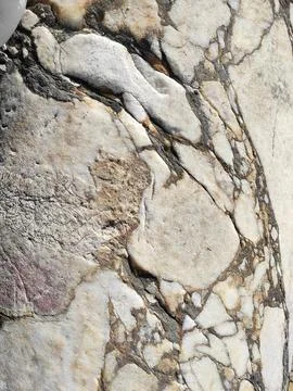 The texture of an old stone wall with pieces of white marble and gray pebbles Stock Photos