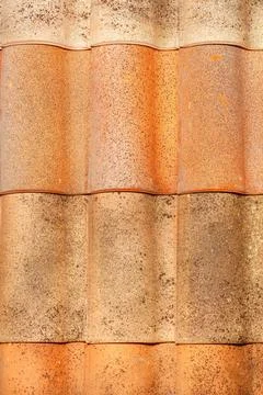 Texture of an old wavy brown tiled roof with splashes. Vertical image. Stock Photos