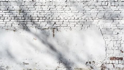 Texture of old white brick wall with destroyed plaster layer and shadows from Stock Photos