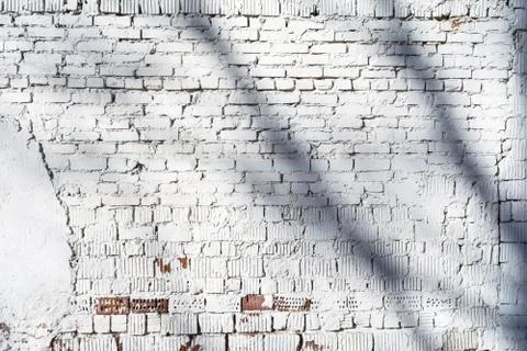 Texture of old white brick wall with destroyed plaster layer and shadows from Stockfoto's