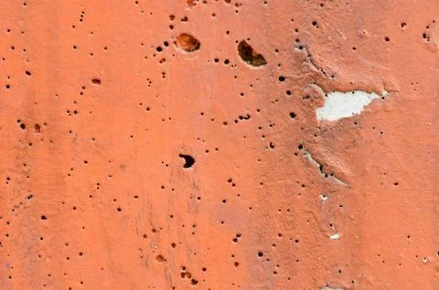 Texture of orange paint concrete surface with several holes. Stock Photos