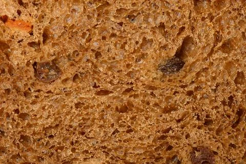 The texture of a porous slice of rye bread with raisins and dried apricots Stockfoto's